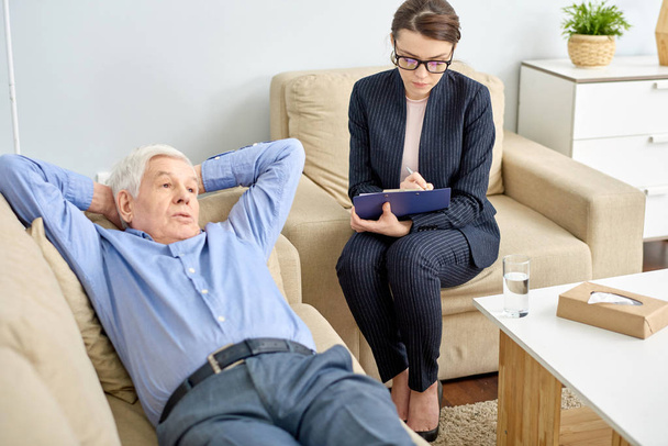 Shot portret starszego człowieka leżącego na wygodną sofę z rękami na karku podczas dyskusji w obliczu problemu z wysoce profesjonalny psychiatra podczas terapii produktywne - Zdjęcie, obraz