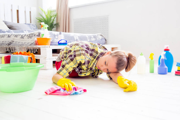 Woman in protective gloves is smiling and wiping dust using a spray and a duster - Photo, Image