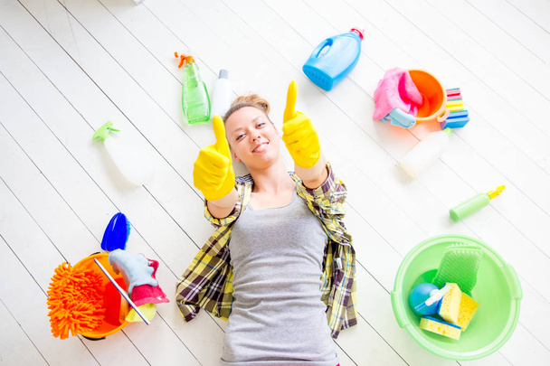 Woman in protective gloves is smiling and wiping dust using a spray and a duster - Foto, imagen