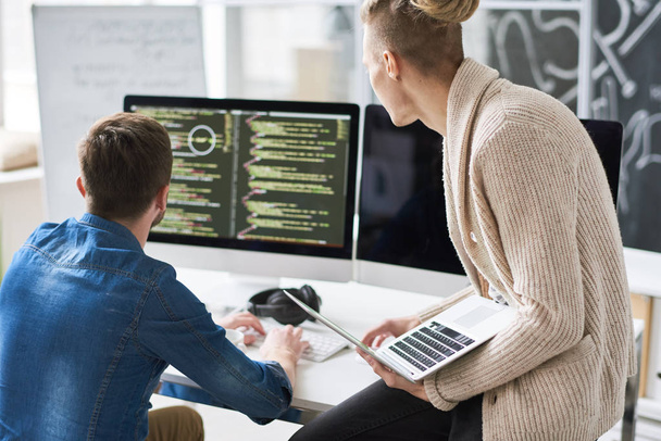 Портрет двух современных веб-разработчиков, пишущих код для программы с помощью компьютеров в современном офисе, копировальное пространство
 - Фото, изображение