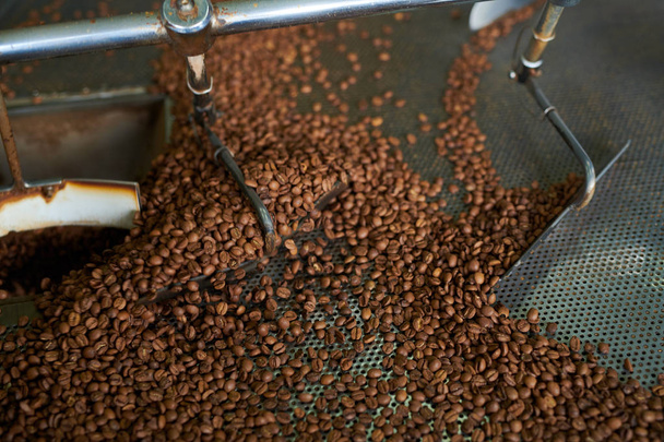Above view closeup of creamy brown coffee beans roasting in drum machine of local artisan roastery, copy space background - Foto, afbeelding