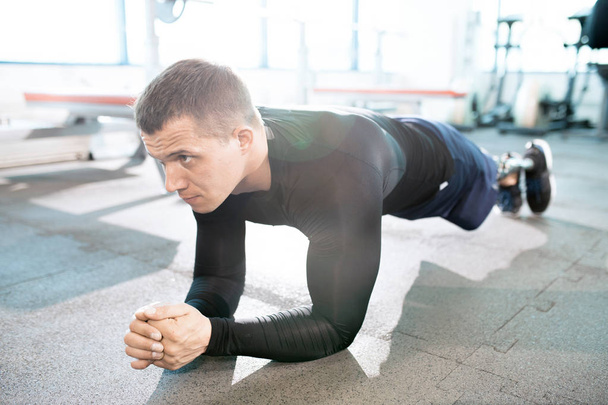 Полноразмерный портрет красивого мускулистого мужчины с протезной ногой, отжимающегося во время тренировки в современном спортзале
 - Фото, изображение