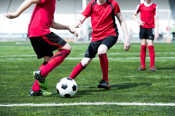 Retrato de seção baixa de dois meninos adolescentes jogando futebol durante a prática da equipe júnior no estádio, espaço de cópia
 - Foto, Imagem