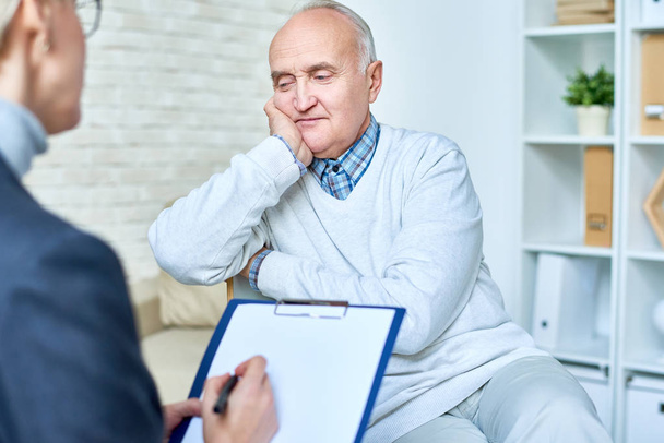 Porträt eines glatzköpfigen älteren Mannes im Gespräch mit einer Therapeutin während der Konsultation, Kopierraum - Foto, Bild