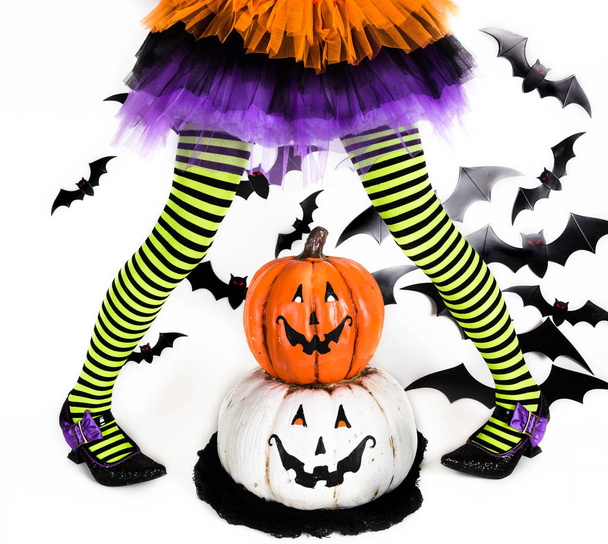 Divertente verde nero Gambe a righe di una bambina con costume di Halloween di una strega con scarpe da strega e sorridente Halloween zucca jack o lanterna
 - Foto, immagini