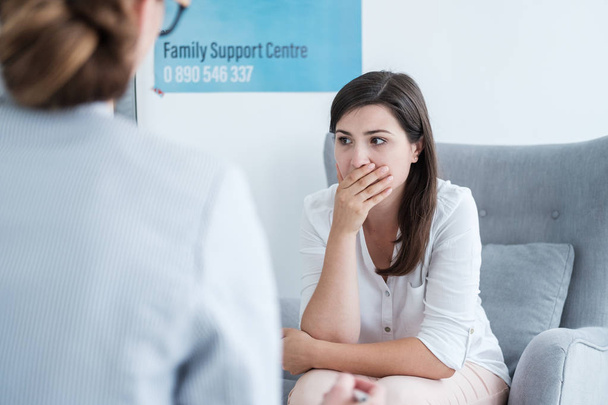 Worried mother holding hand on her mouth during a visit at family support center - Photo, image