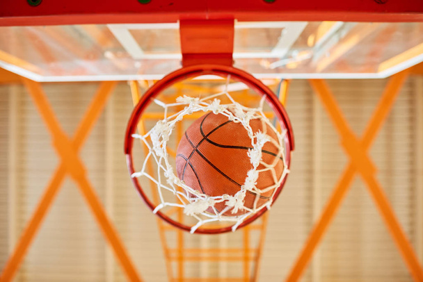 знизу постріл баскетбольний м'яч падає через мережу в тренажерному залі
.  - Фото, зображення