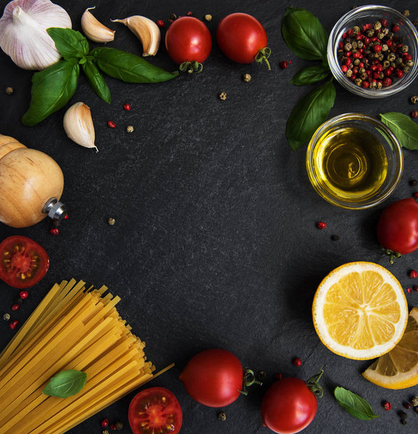 italienische Lebensmittelzutaten. Nudeln, Tomaten, Basilikum und Gewürze auf schwarzem Hintergrund - Foto, Bild