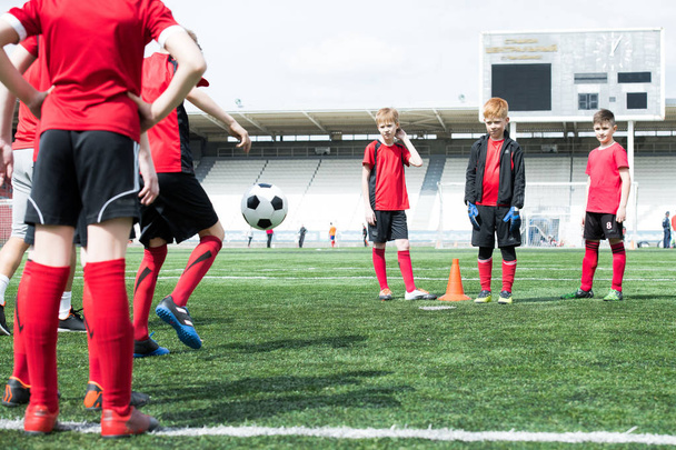 Ganztägiges Porträt des Trainings der Juniorenfußballmannschaft, Fokus auf drei Teenager-Jungs, die Schlange stehen, Kopierraum - Foto, Bild