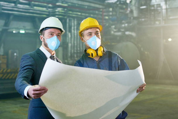 Талия портрет бизнесмена и рабочего обсуждают инженерные планы на заводе, как носить защитные маски и каски, копировать пространство
 - Фото, изображение