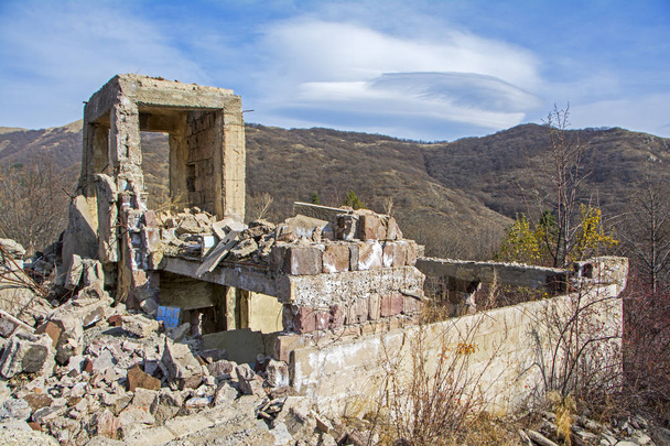 Apocalyptic landscape with destroyed building in a wasteland with mountains on background. Devastation and war concept - Photo, Image