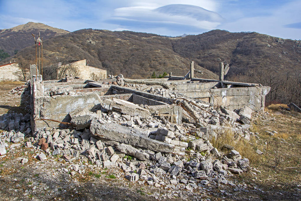 Апокалиптический пейзаж с разрушенным зданием в пустоши с горами на заднем плане. Концепция опустошения и войны
 - Фото, изображение