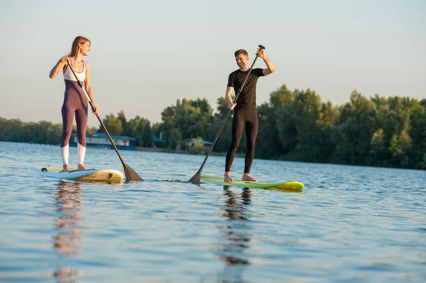 Happiness boy and girl on sup surf swimming at the river. Concept lifestyle, sport, love concept - 写真・画像