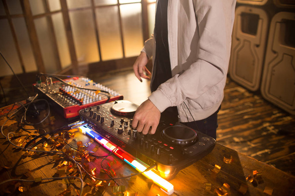 Alto ângulo de perto de DJ jovem tocando música no clube da moda, foco em mãos sobre misturador DG com luzes iluminadas, espaço de cópia
 - Foto, Imagem