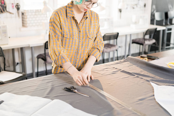 Porträt einer Schneiderin, die einen Stoff mit weißer Kreide schneidert, während sie maßgeschneiderte Kleidung näht, Kopierraum - Foto, Bild