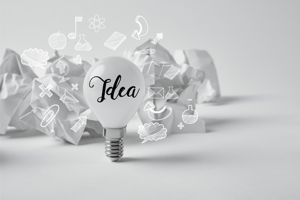 light bulb with crumpled papers on white with idea sign and icons - Photo, Image