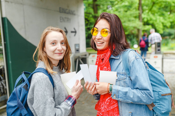 Δύο κορίτσια ευτυχισμένος φοιτητής στην είσοδο του ζωολογικού κήπου με εισιτήρια - Φωτογραφία, εικόνα