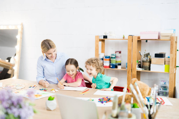 Retrato de duas crianças felizes desfrutando de arte e aula de artesanato com o jovem professor na escola de desenvolvimento, espaço de cópia
 - Foto, Imagem