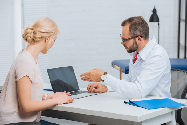 fisioterapeuta em casaco branco tendo conversa com paciente do sexo feminino no local de trabalho com laptop no hospital
 - Foto, Imagem
