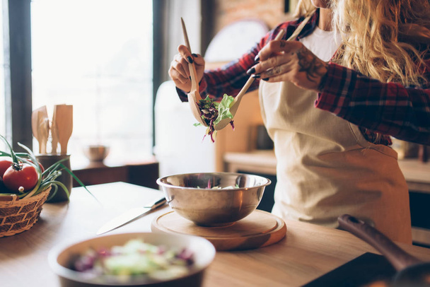 キッチン インテリアの背景に新鮮なサラダを調理エプロンの主婦。ハッピー女性のコック。シェフによる食事の準備 - 写真・画像