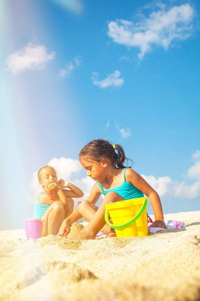Kinderen op het strand. Mooie meisjes spelen op het zand bij de zee. - Foto, afbeelding