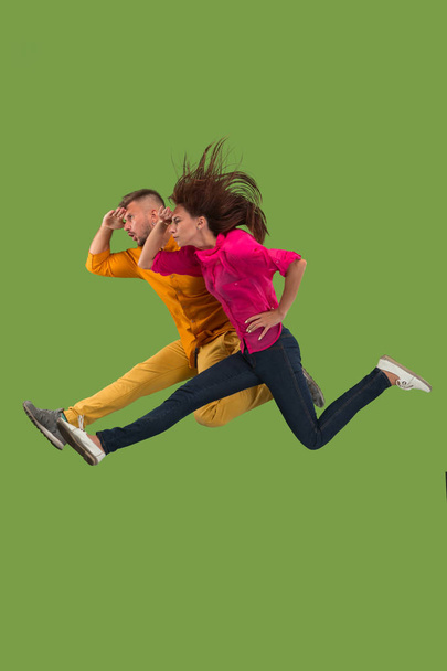 Freiheit in der Bewegung. hübsches junges Paar springt vor grünem Hintergrund - Foto, Bild