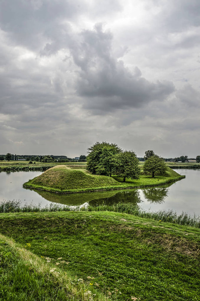 View from the ramparts of the fortified town of Leusden, The Netherlands towards an island in the surrounding moat under a dramatic sky - Foto, Imagen