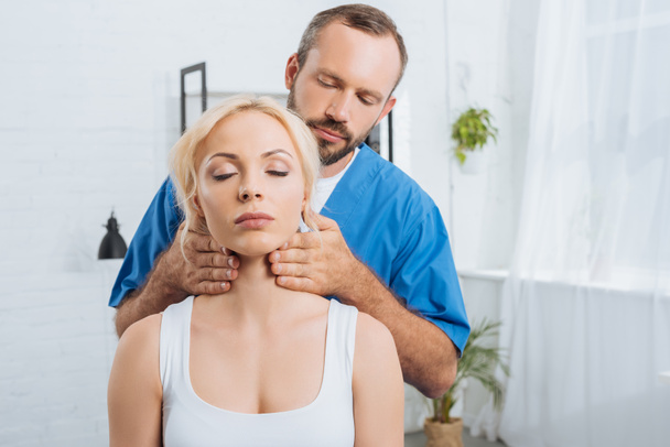 retrato de masajista terapeuta masajeando cuello de mujer joven en clínica
 - Foto, Imagen