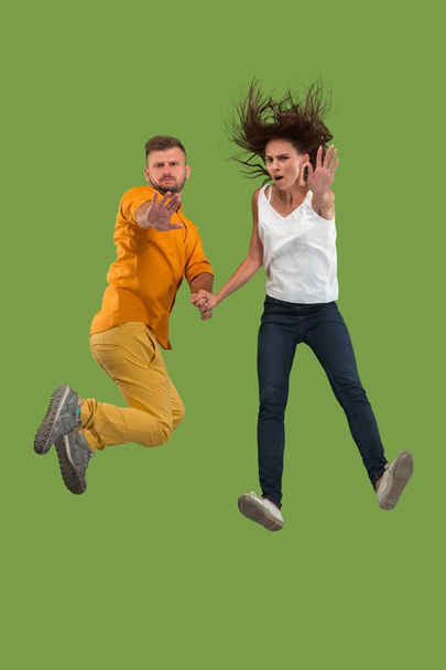 Freedom in moving. Pretty young couple jumping against green background - Foto, afbeelding