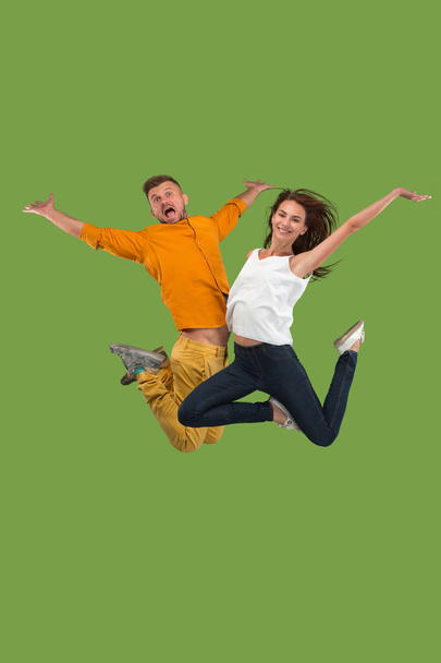Freedom in moving. Pretty young couple jumping against green background - Фото, изображение