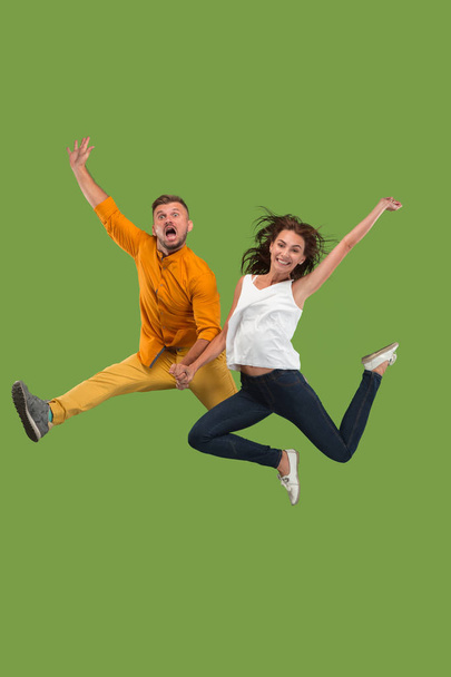 Freedom in moving. Pretty young couple jumping against green background - Photo, image