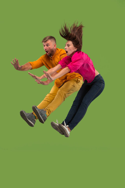 Freedom in moving. Pretty young couple jumping against green background - Фото, зображення