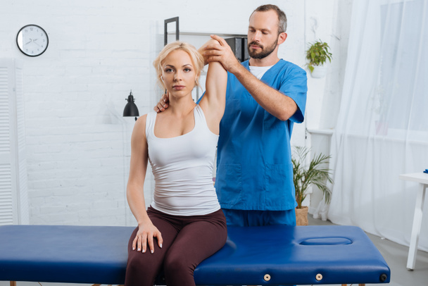 retrato de quiroprático esticando braço de mulheres na mesa de massagem na clínica
 - Foto, Imagem