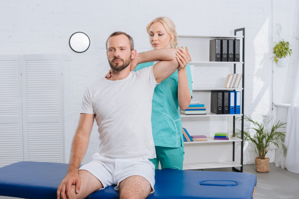 Porträt des Physiotherapeuten, der seinen Arm im Krankenhaus ausstreckt - Foto, Bild