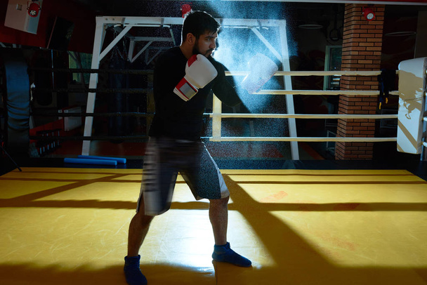 Dramático retrato de comprimento total de difícil treinamento de lutador do Oriente Médio no ringue de boxe com fumaça no fundo, cópia, espaço
 - Foto, Imagem