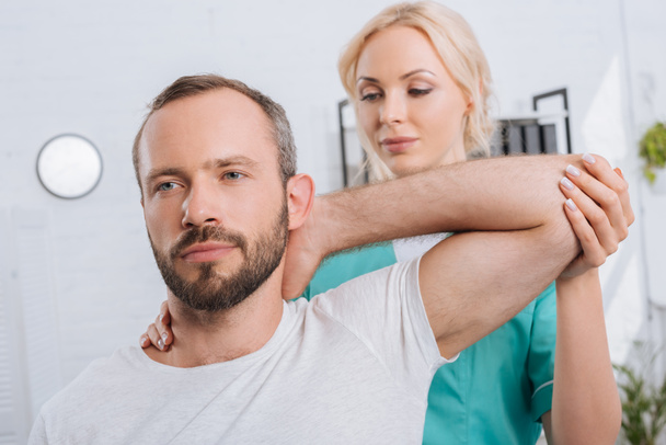portrait of physiotherapist stretching mans arm in hospital - Zdjęcie, obraz