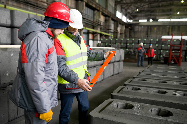 Portrait of two modern factory workers inspecting quality of production at graphite plant, copy space - Photo, Image