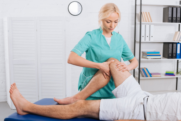 vue partielle du chiropraticien massant la jambe des patients lors d'un rendez-vous en clinique
 - Photo, image