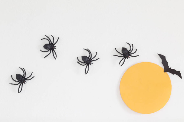 Decoraciones para el hogar de Halloween con arañas y murciélago sobre fondo de pared blanco, concepto mínimo, disposición plana, vista superior, luz natural
 - Foto, imagen