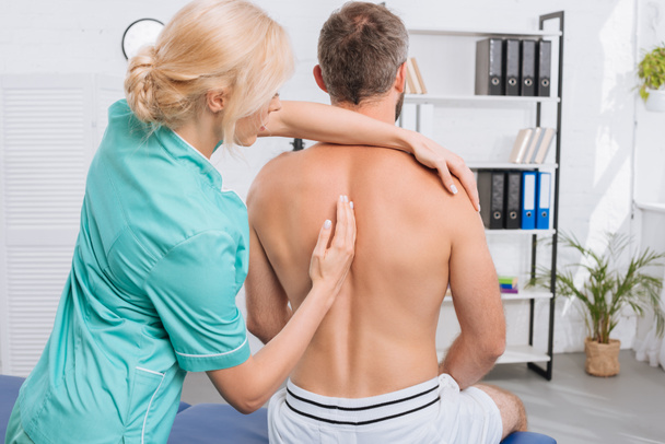 Widok człowieka mając chiropraktyka korekty w klinice z tyłu - Zdjęcie, obraz