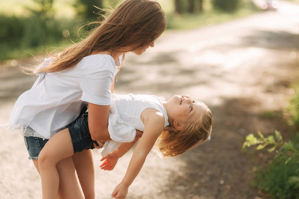 niña jugando con mamá en el parque en el día de verano durante el atardecer
 - Foto, Imagen
