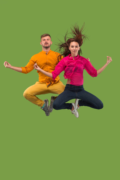 Freedom in moving. Pretty young couple jumping against green background - Φωτογραφία, εικόνα