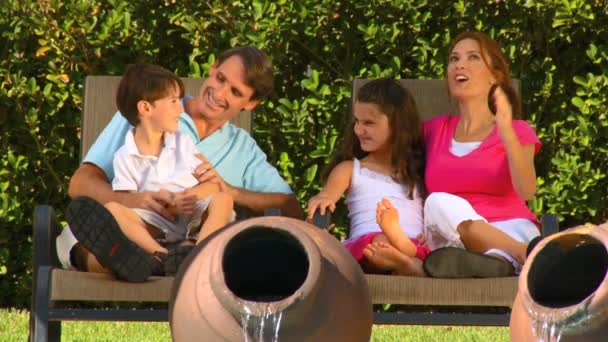 Houkutteleva nuori valkoihoinen perhe nauttii vapaa-ajasta ulkona puutarhassaan
 - Materiaali, video