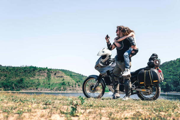 Fiatal romantikus pár szórakozás a folyóparton egy off road turista motorkerékpár. Szerelem, szabadság, összetartozás. Boldog fiú és lány utazás egy motorkerékpár, enduro túra - Fotó, kép