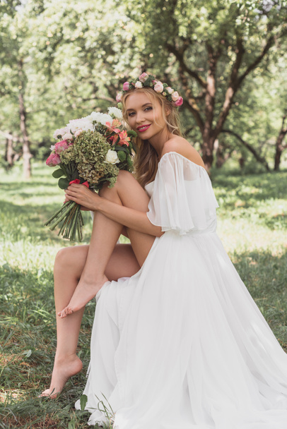 bela jovem noiva descalça segurando buquê de flores e sorrindo para a câmera
 - Foto, Imagem