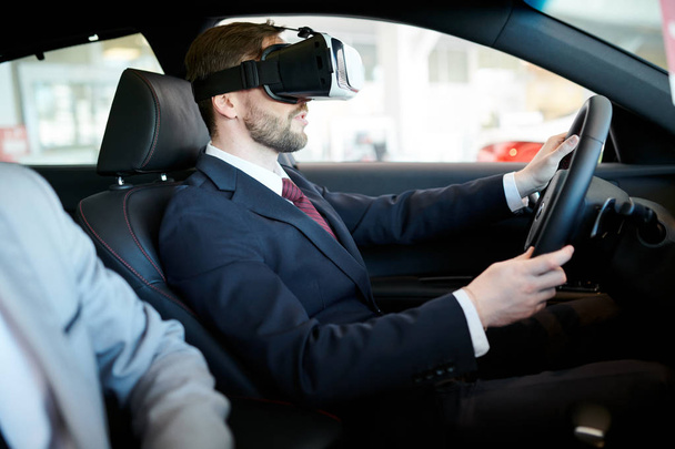 Side view portrait of handsome businessman wearing VR headset driving luxury car, modern technology concept - Photo, Image