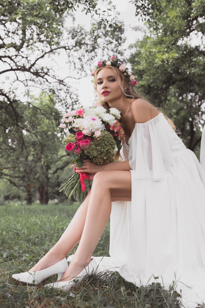 beautiful young bride sitting on chair and looking at camera outdoors - Fotografie, Obrázek
