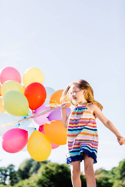 Happy girl with bunch of colorful balloons. - Фото, изображение