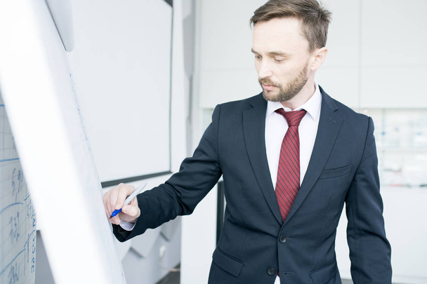 Cintura-se retrato de belo empresário escrevendo no quadro branco e explicando estratégia de marketing durante reunião na sala de conferências
 - Foto, Imagem