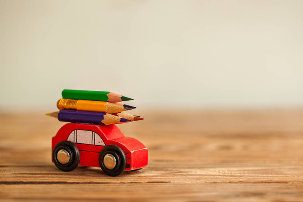 Miniature Red Car Carrying a colorful pencils on wooden table. Back to school concept. - Zdjęcie, obraz